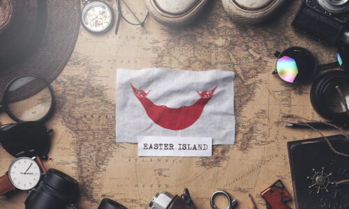 Bandera de la Isla de Pascua entre los accesorios de viaje en un mapa antiguo. Fotografía cenital.
