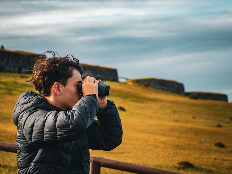 Joven viajero explorando Orongo, Rapa Nui con binoculares